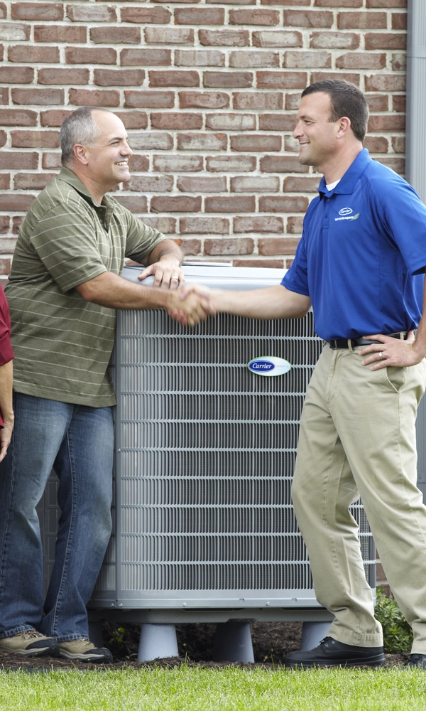 carrier tech shaking hands with man in front of unit outdoor